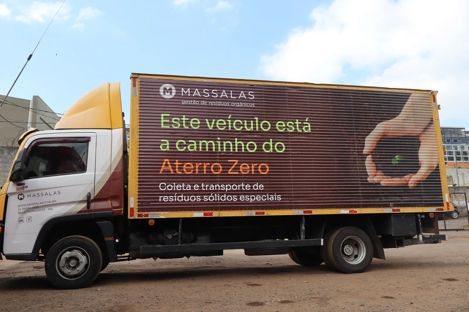 Caminhão baú da Massalas visto de lado, com a plotagem "Este veículo está a caminho do Aterro Zero".
